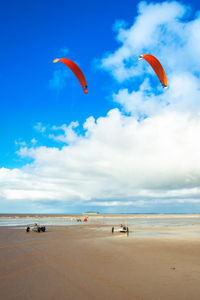 People paragliding at beach against sky