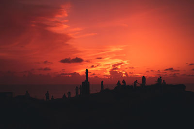 Silhouette people on beach against sky during sunset