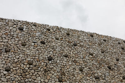 Low angle view of stone wall against sky