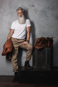 Portrait of young man sitting against wall