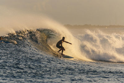 Man surfing in sea against sky