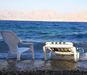 Chairs and tables on beach against sky