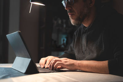 Mid aged businessman using tablet and the internet working from home in coronavirus lockdown.