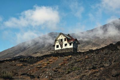 Low angle view of house on mountain against sky