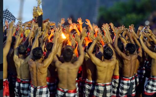 Shirtless men with arms raised dancing outdoors