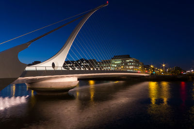 Illuminated bridge over river at night