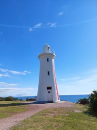 Lighthouse by sea against sky