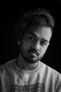Portrait of young man against black background