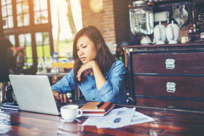 Woman using phone while sitting on table