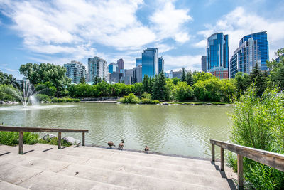 River by modern buildings in city against sky