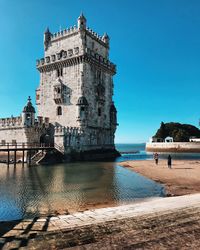 View of building by sea against clear blue sky