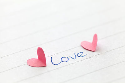 Close-up of love text by heart shape on paper