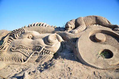 Statue on sand against clear sky