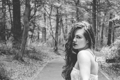 Portrait of woman standing on road amidst trees