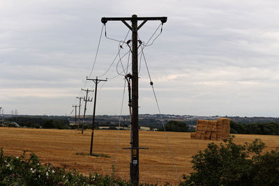 Electricity pylon on field against sky