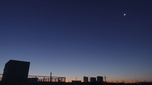 Low angle view of silhouette buildings against blue sky