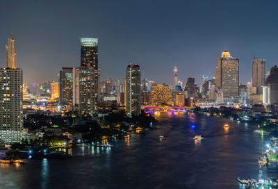 Illuminated buildings and river in city at night