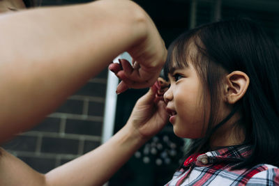 Cropped hands of barber cutting hair of girl