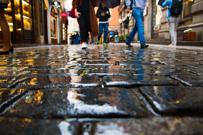 Low section of people walking on wet street during monsoon