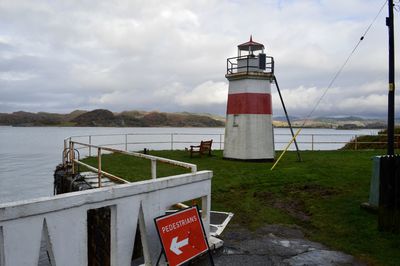 Lighthouse by sea against sky