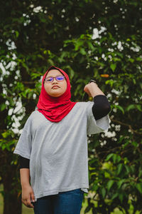 Portrait of young woman standing against plants