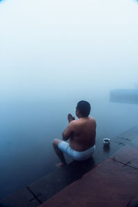 Rear view of man sitting in swimming pool