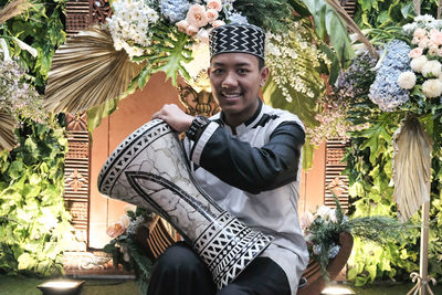 Portrait of smiling young man sitting against plants