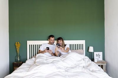 Young man using mobile phone while sitting on bed