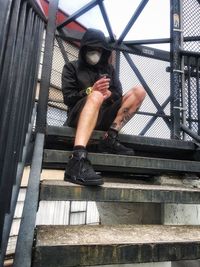 Low angle view of man photographing on metal structure