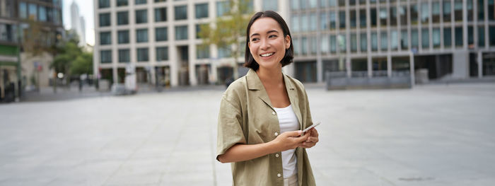 Portrait of young woman standing in city