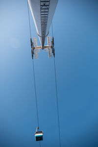 Low angle view of overhead cable car against clear blue sky