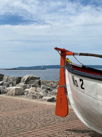 Boat moored by beach against sky