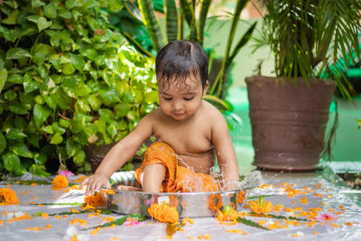 Cute toddler baby boy bathing in decorated bathtub at outdoor from unique perspective