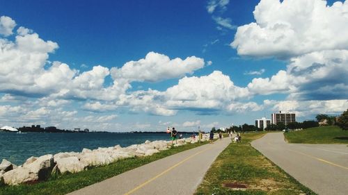 View of road by sea against cloudy sky