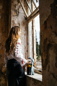 Rear view of young woman standing against wall