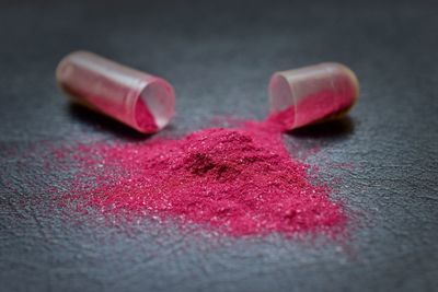 Shiny pink powder spilled from open capsule on table