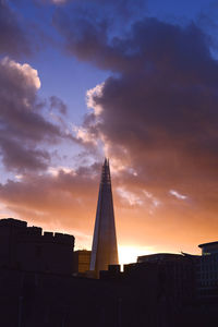 Low angle view of building against cloudy sky at sunset