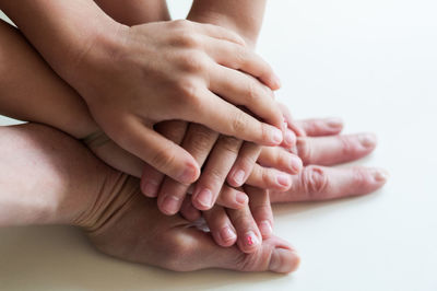 Cropped image of family hands stacking on white table