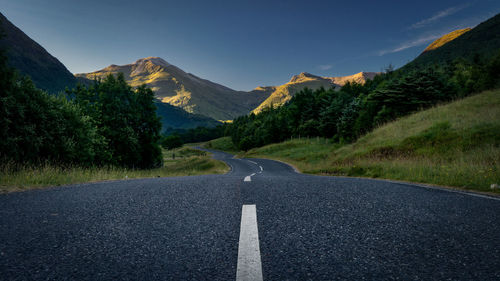 View of road amidst mountains against blue sky