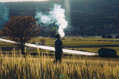 Rear view of man smoking while walking on field