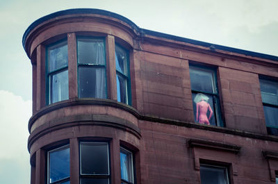 Low angle view of mannequin seen through building window