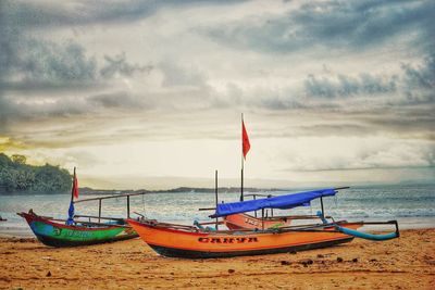 Boat moored on beach against sky