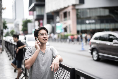 Young man looking away on street in city