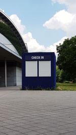 Information sign by building against sky