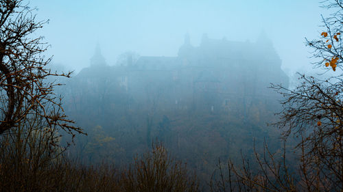 Scenic view of trees and buildings against sky during winter