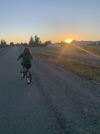 Rear view of man riding bicycle on road against sky