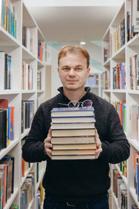 Portrait of smiling young woman standing in library