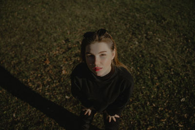 Portrait of a girl from above on a background of green grass, a woman with red lipstick on her lips