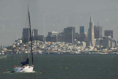 Boat sailing on river in city against sky