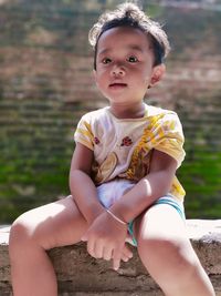 Portrait of cute boy sitting outdoors